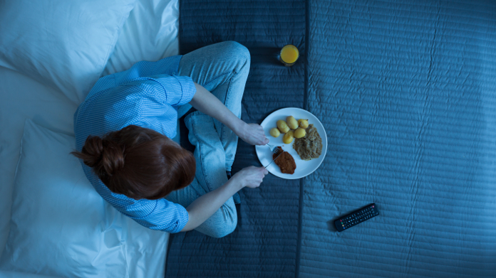 Woman eating at night in bed