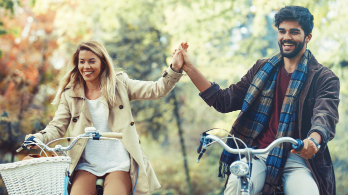 Pareja enérgica en bicicleta en el bosque en otoño