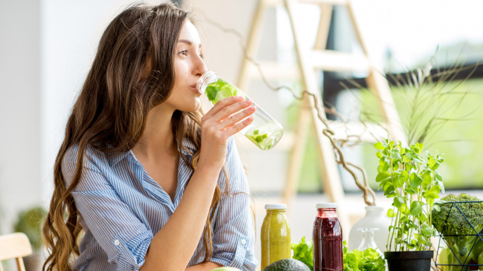 Jonge vrouw die een detox-sapje drinkt