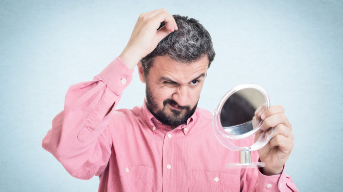 Homme qui voit ses cheveux blanchir dans le miroir