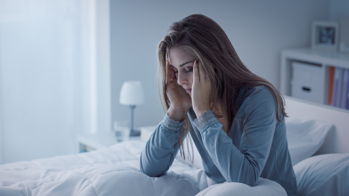 Mulher deitada na cama, que tem problemas em dormir 